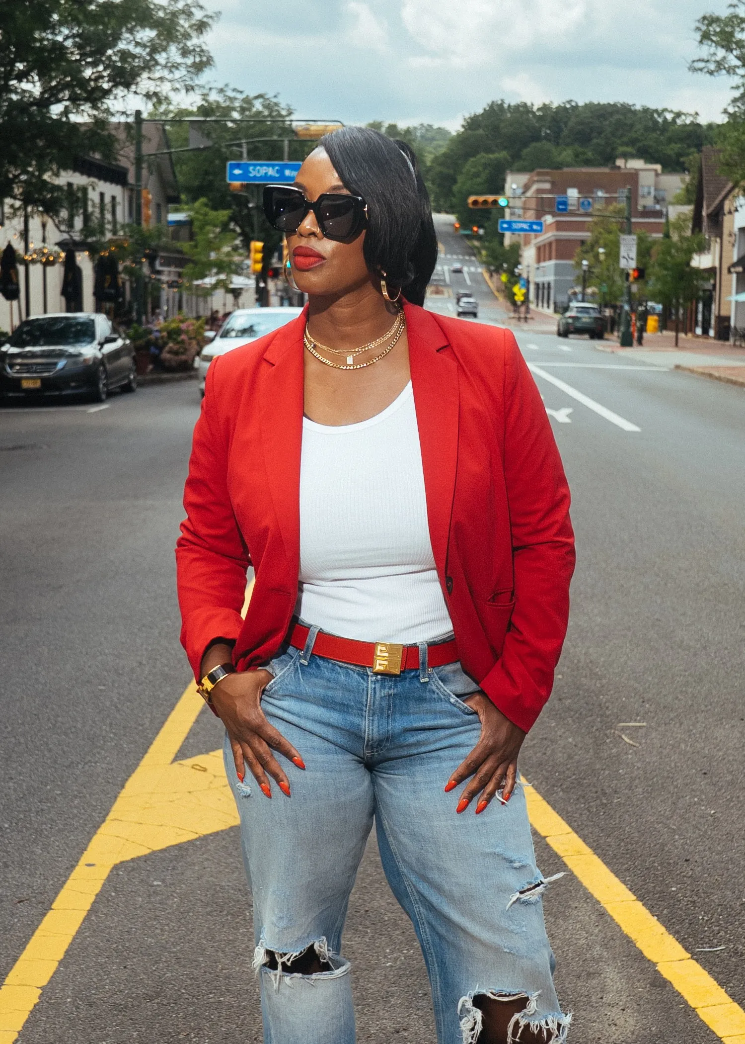 Dr. Syreeta McClain standing in the middle of a downtown street in a red blazer and jeans.